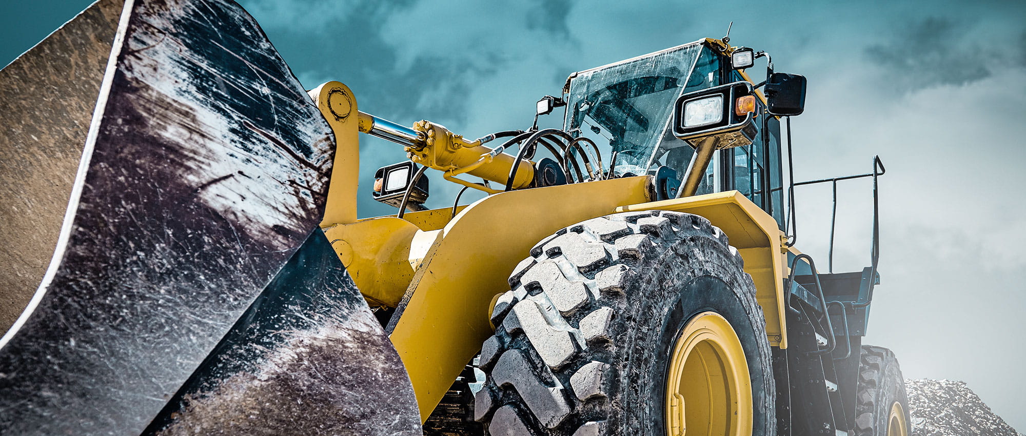 Front loader construction machine in front of cloudy sky