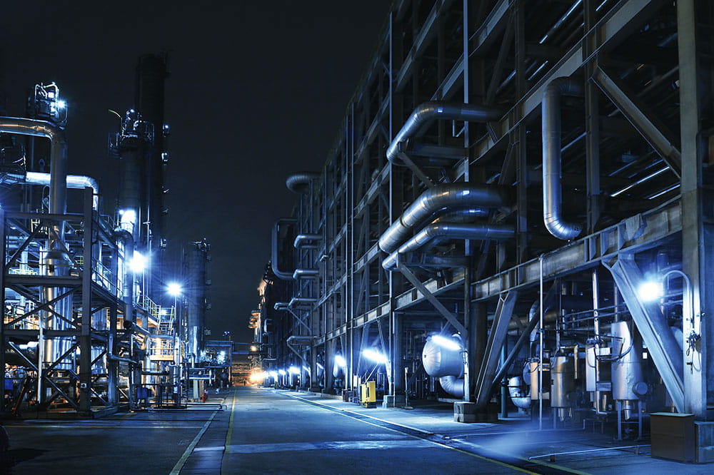 Chemical plant at night with several pipes in blue color scheme.