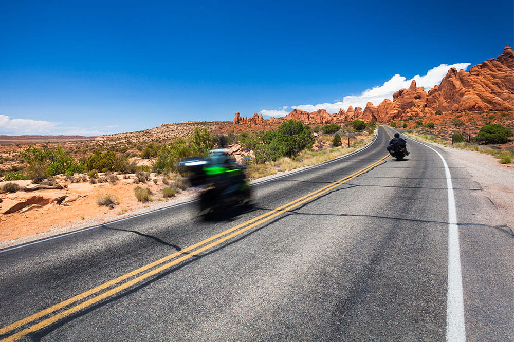 Two motorcyclists on a barren country road in the desert 